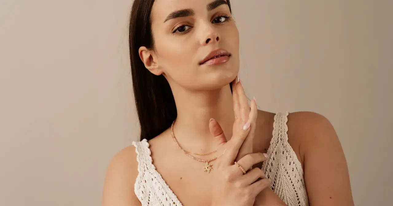 Delikatny choker z zawieszką w kształcie słońca, noszony przez kobietę z subtelnym makijażem.
