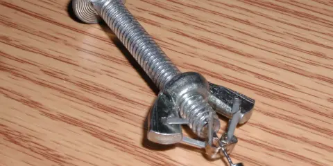 Jak zdjąć kolczyki wkręty? Metalowy element imitujący śrubę z nakrętką i zaczepem, na którym wisi mały kolczyk.