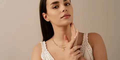 Delikatny choker z zawieszką w kształcie słońca, noszony przez kobietę z subtelnym makijażem.