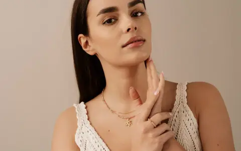 Delikatny choker z zawieszką w kształcie słońca, noszony przez kobietę z subtelnym makijażem.