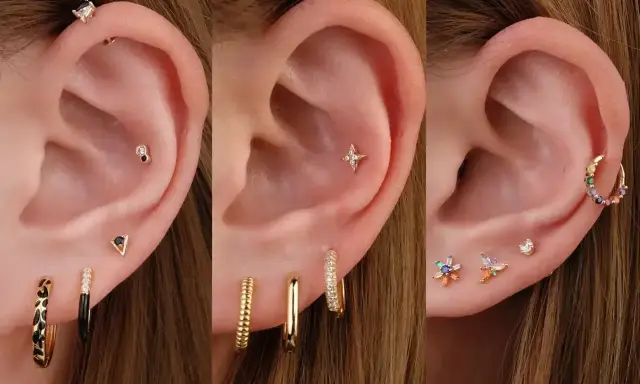 Ucho z wieloma kolczykami: helix, płatek, tragus. Złote, kolorowe, z cyrkoniami.