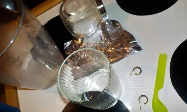 Przygotowania do czyszczenia złota folią aluminiową: szklanka, słoik, folia, łyżeczka i kolczyki.